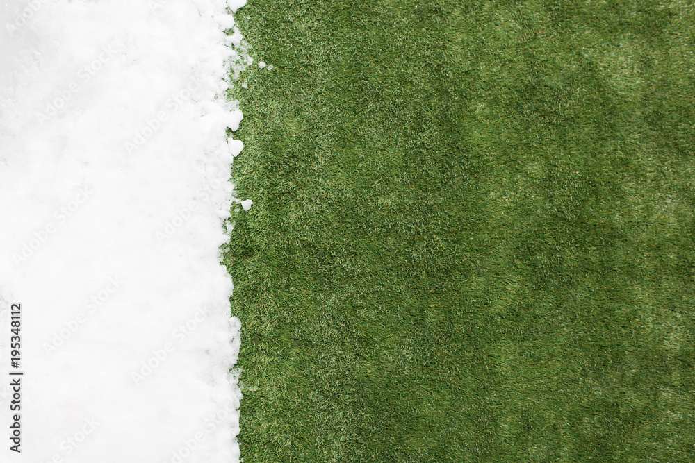 Fototapeta premium Meeting snow on green grass close up - between winter and spring concept background