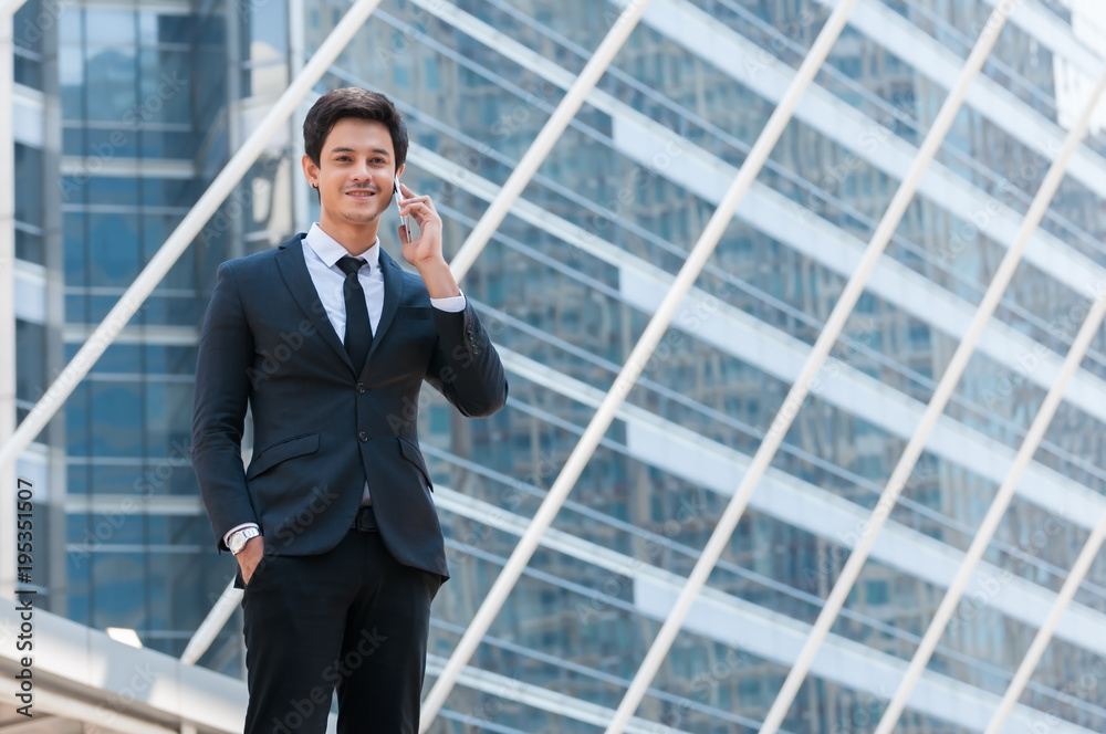 Young handsome business man smile and standing use smartphone between big building in city, man happy after project successful. Young handsome business man smile and standing use smartphone between big building in city, man happy after project successful.