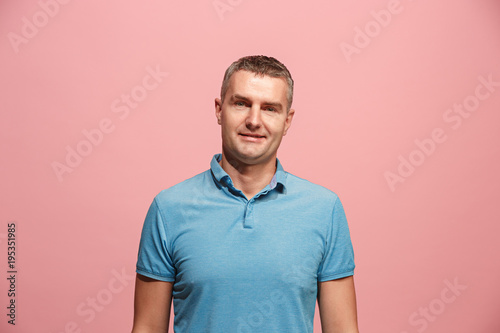 The happy business man standing and smiling against pink background.
