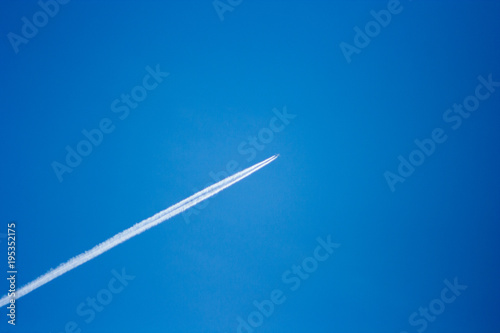 streak of an airplane flying in the clear blue sky photo