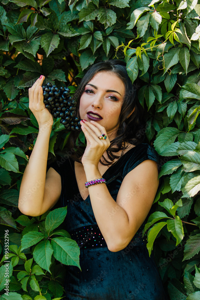 Portrait of young sexy brunette with black grapes. Portrait of young sexy brunette with black grapes.