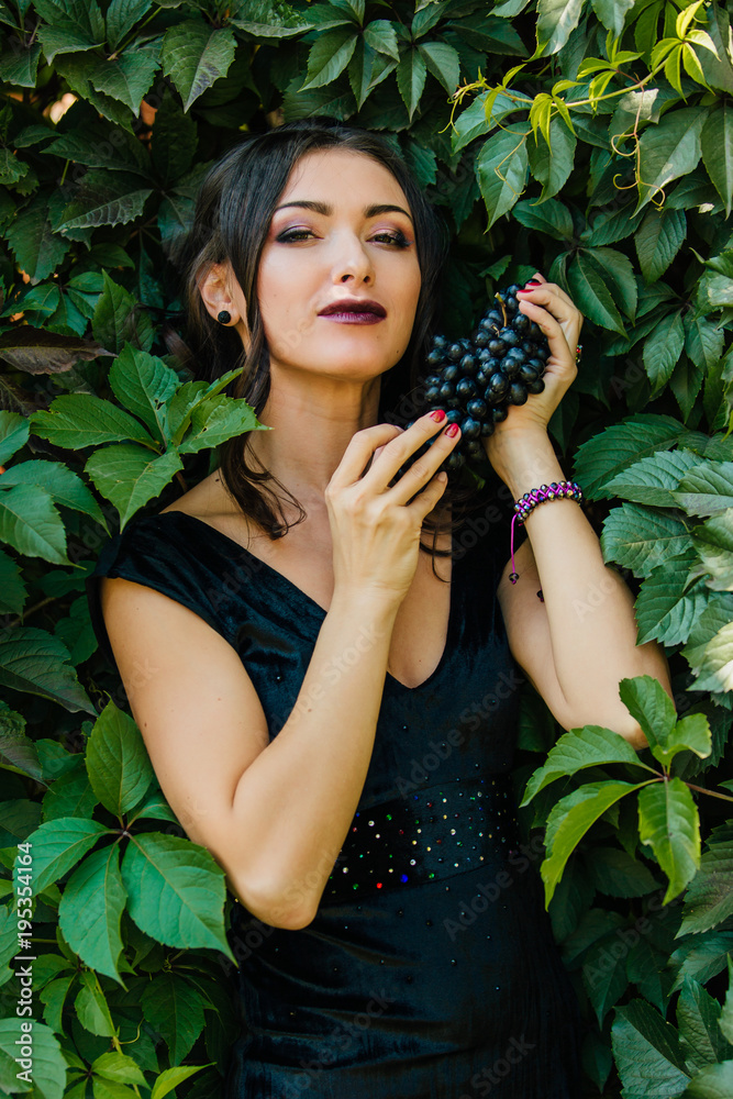 Portrait of young sexy brunette with black grapes. Portrait of young sexy brunette with black grapes.