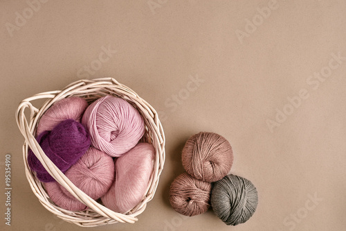 Balls of yarn and knitting needles. Colored yarn for knitting in a wicker bowl on a beige background. photo