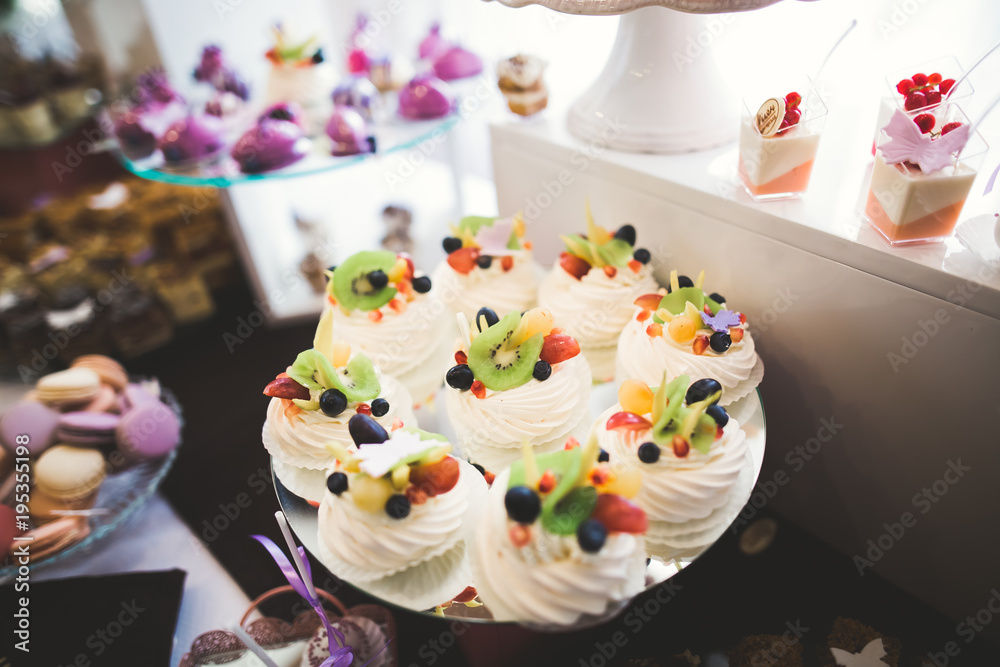 Delicious and tasty dessert table with cupcakes shots at reception closeup
