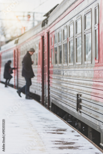 Silhouette of blurred passengers enters the train in winter, outdoor. Passenger transportation in the city.