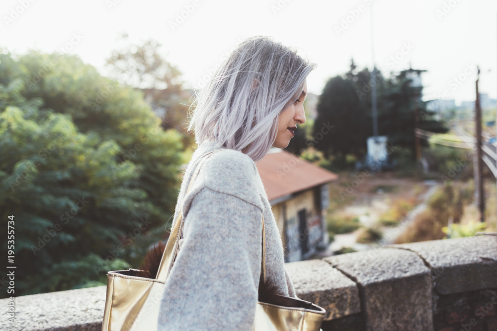 Waist up of young beautiful caucasian purple grey hair woman outdoor in the city looking over, smiling - happiness, carefree, serene concept Waist up of young beautiful caucasian purple grey hair woman outdoor in the city looking over, smiling - happiness, carefree, serene concept