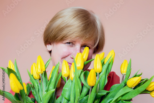 woman with bouquet of yellow tulips mysteriously smiling, birthday present
