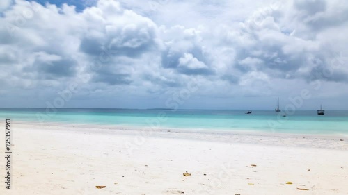 Panoramic longexposure Timelapse of white sand tropical beach with turquoise water, coconut trees swaying in the wind and clouds passing by. Nungwi beach, Zanzibar, Tanzania.