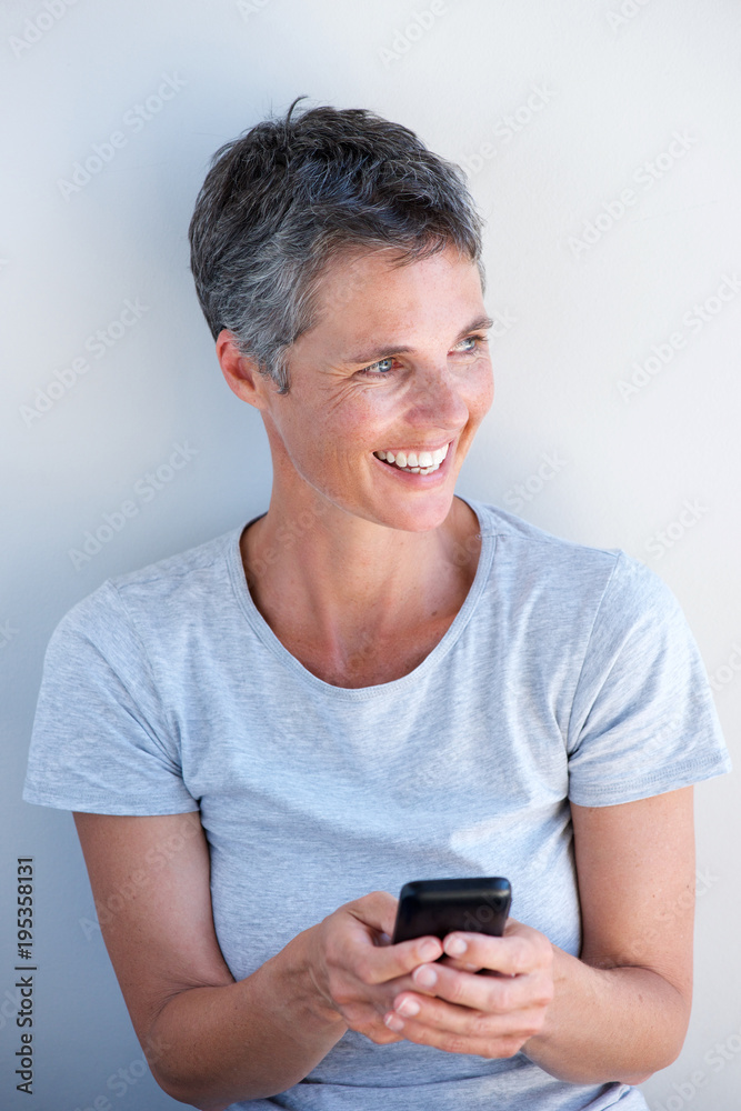 smiling older woman holding mobile phone in hand smiling older woman holding mobile phone in hand