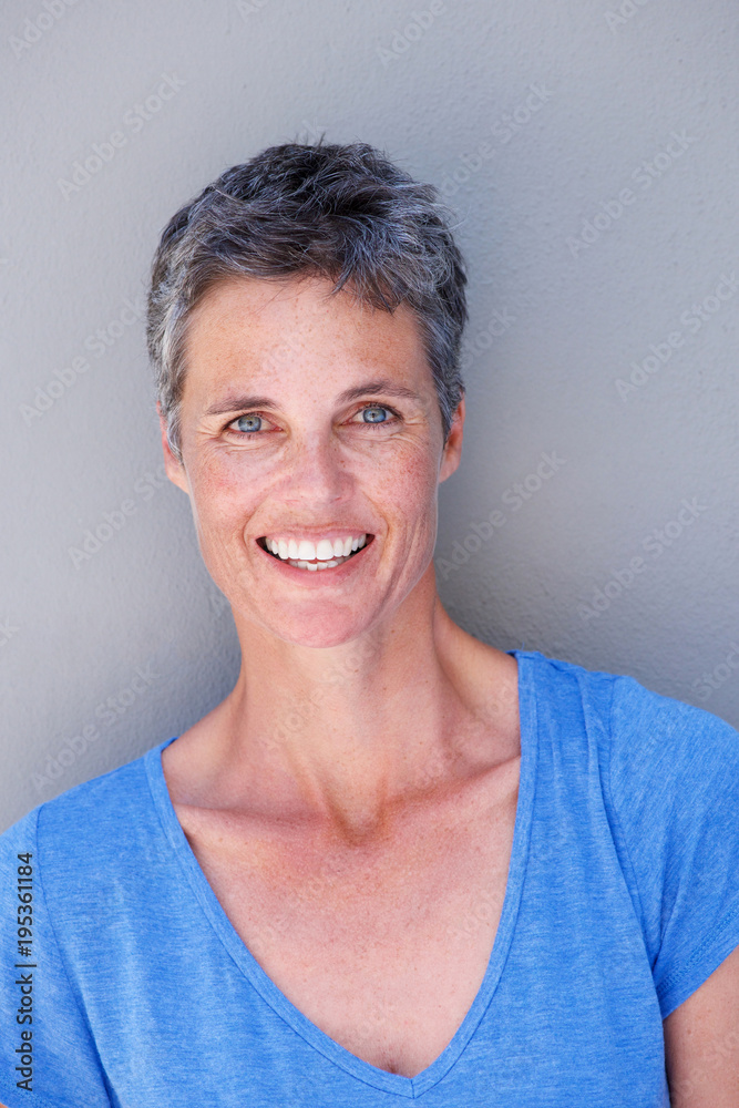 happy older woman smiling against gray background happy older woman smiling against gray background