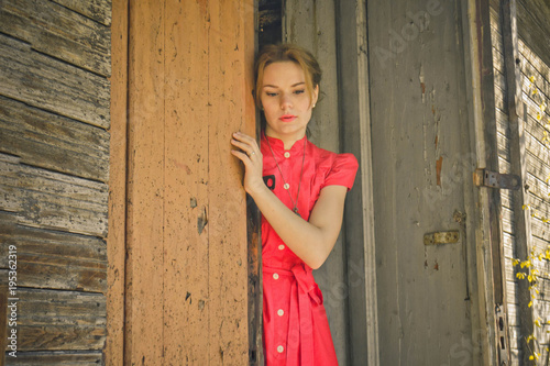 girl in red dress near the old wooden house