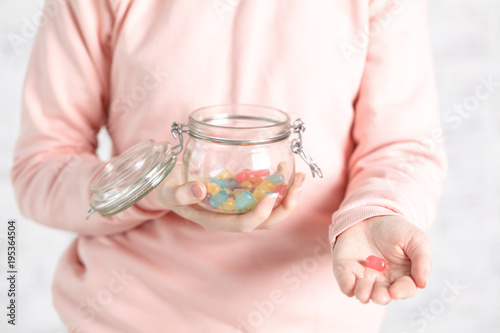 female hold assortment of colored jely candy in jar