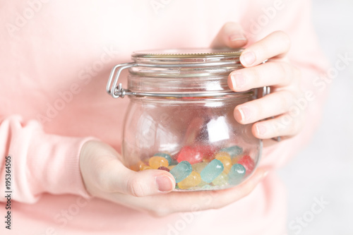 female hold assortment of colored jely candy in jar