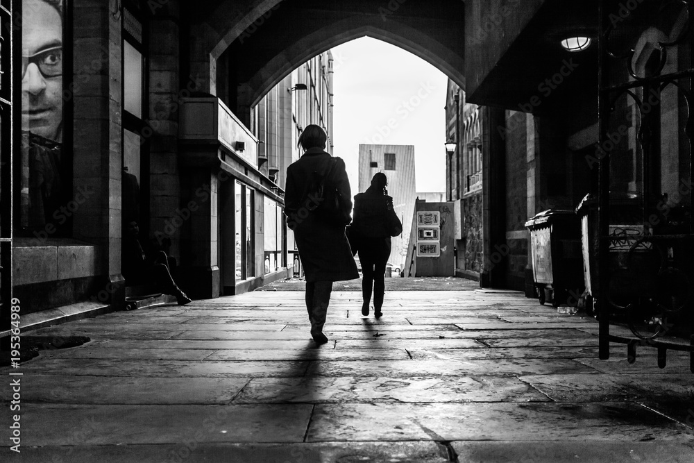 silhouettesof people walking through an alley way