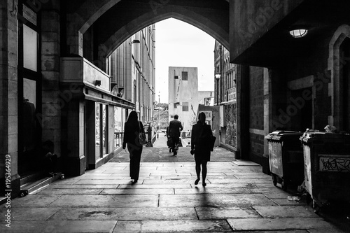 silhouettesof people walking through an alley way