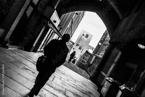 silhouettesof people walking through an alley way