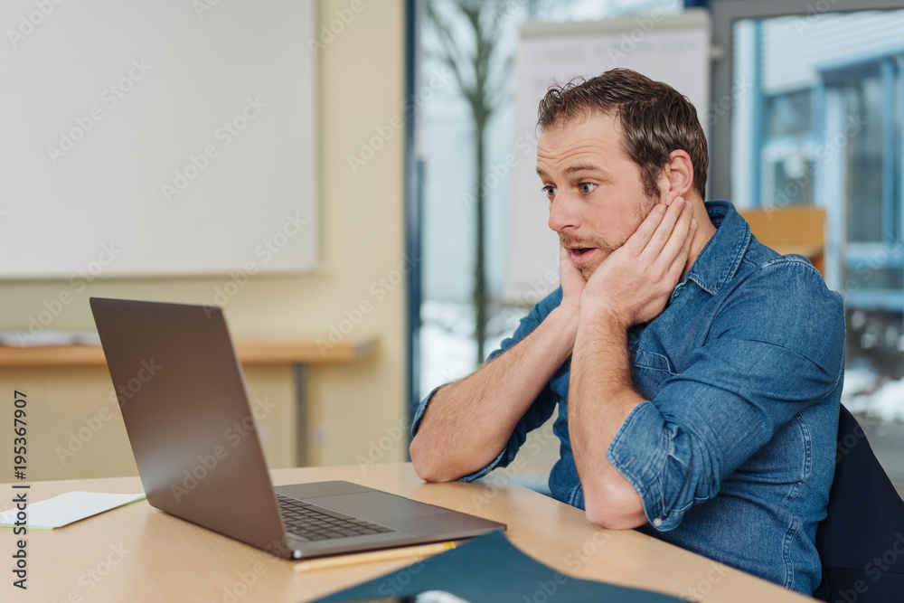 Surprised man looking at laptop screen Surprised man looking at laptop screen