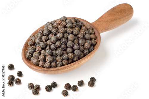 dried black peppercorns in the wooden spoon, isolated on white