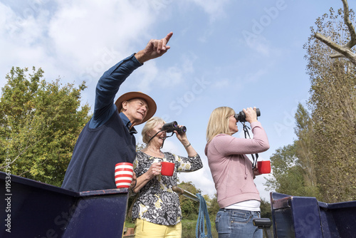 Obraz na plátne Group of people on a boating holiday using binoculars to spot wildlife along the
