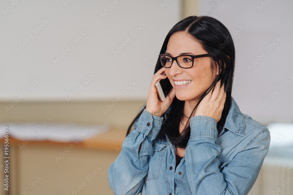 Cheerful woman talking on mobile phone in office Cheerful woman talking on mobile phone in office