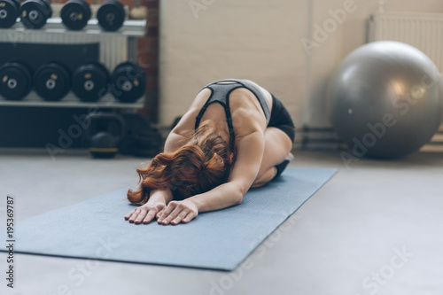 Young woman doing exercises on a mat in a gym