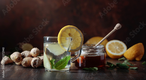 Ginger tea with honey , lemon and mint on old wooden table .