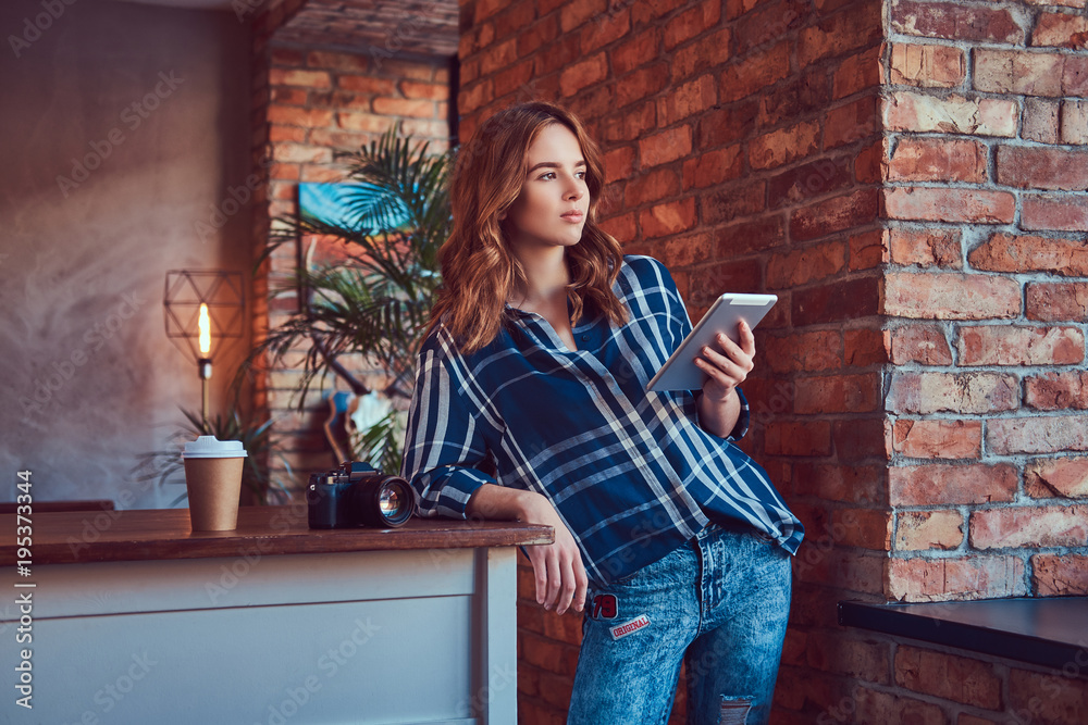 Young charming girl photographer working with a tablet in a stud