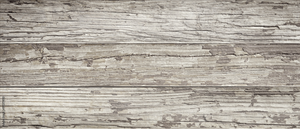 Aged wooden background of weathered distressed rustic wood boards with faded paint showing brown woodgrain texture