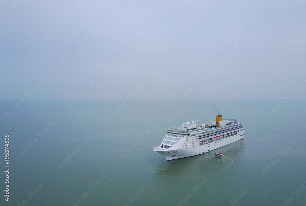 White luxury cruise ship docked in beautiful Caribbean sea close to the beach.