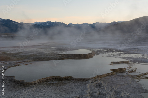 Waterfilled limestone terraces at Mammoth Hot Springs at dawn when the early morning fog is still present