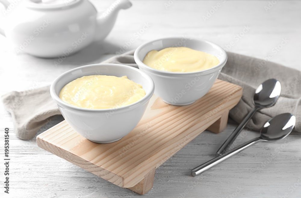 Bowls with vanilla pudding on wooden board Bowls with vanilla pudding on wooden board