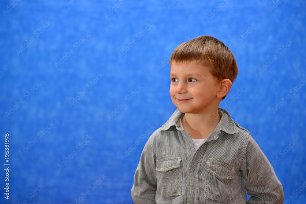 Boy in the studio on a blue background looking out into the distance Boy in the studio on a blue background looking out into the distance