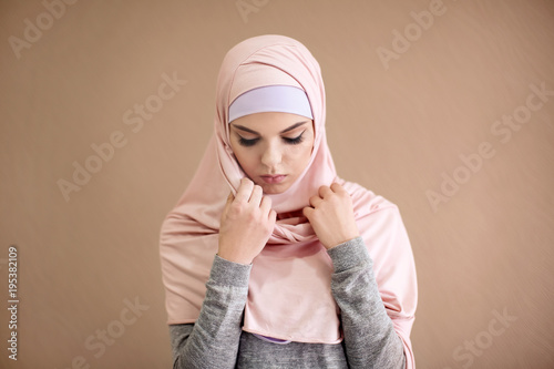 Young Muslim woman praying on color background © Africa Studio