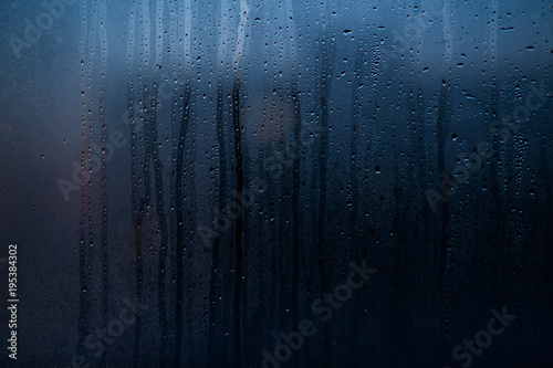 Flowing down water drops on window glass