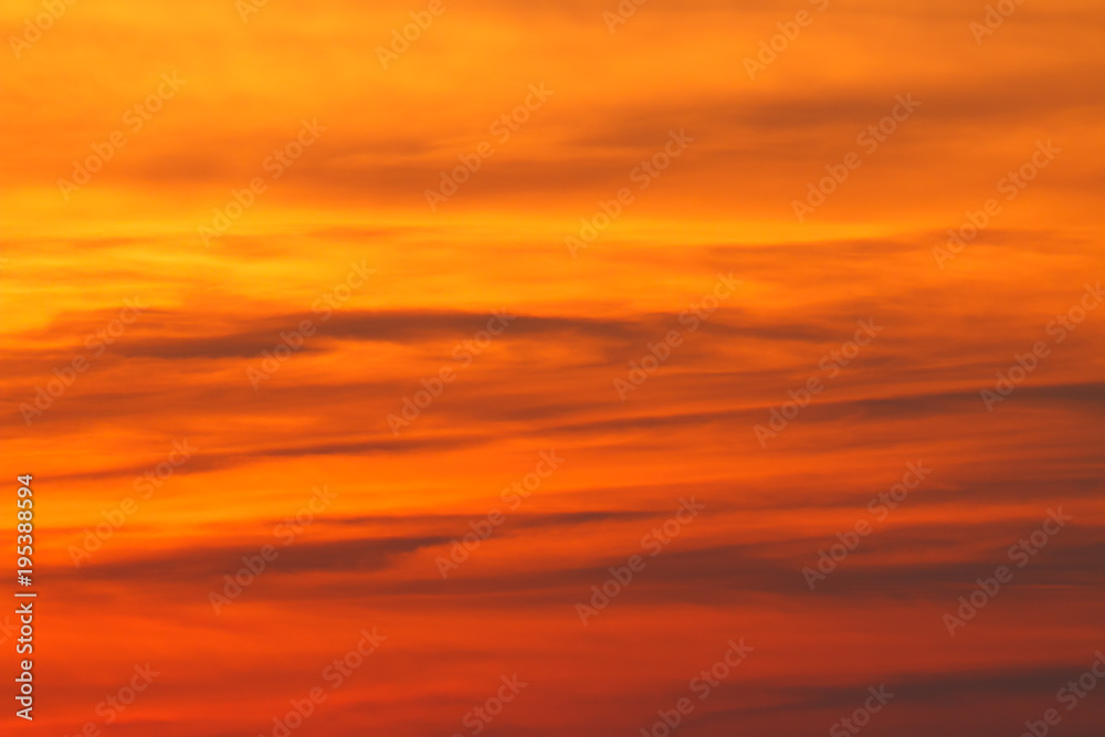 red big sun obscured by clouds near the horizon at sunset or sunrise. The sun is partially seen through the clouds 
