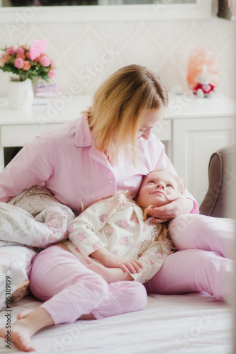 a mother tenderly embraces her daughter on the bed 