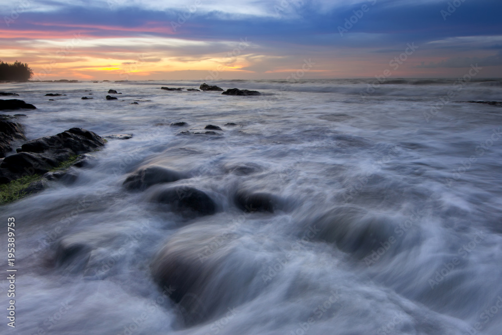 Seascape with rocks covered by green moss during sunset.