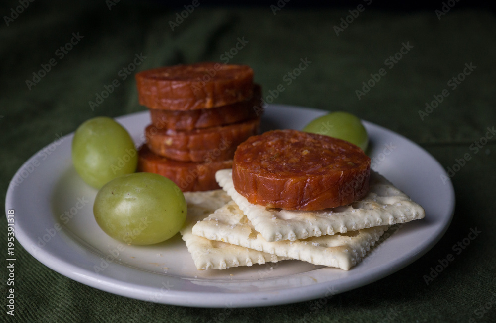 Pepperoni, grapes, and crackers on a snack plate Pepperoni, grapes, and crackers on a snack plate