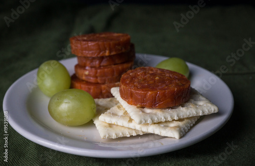 Pepperoni, grapes, and crackers on a snack plate