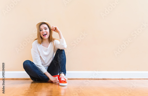 Happy young woman in a hat smiling in a big open room