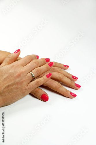 Two female hands in elegant pose with pale pink painted nails on a white surface