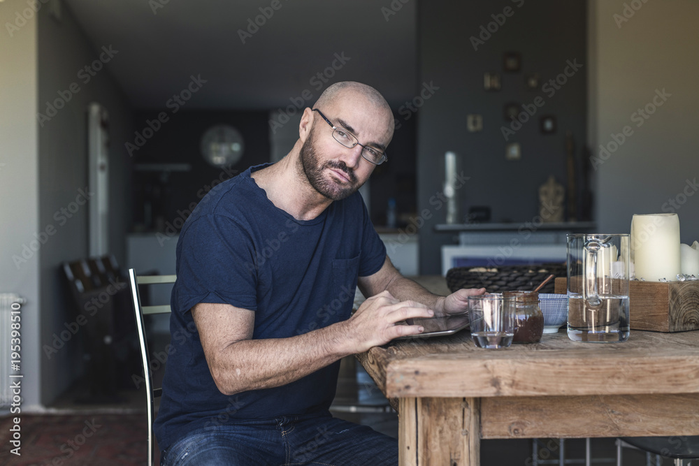 Portrait of a stylish man in his private home while is checking a to do list, working on his tablet and taking his break fast. Modern house and a business man in a private situation. Portrait of a stylish man in his private home while is checking a to do list, working on his tablet and taking his break fast. Modern house and a business man in a private situation.