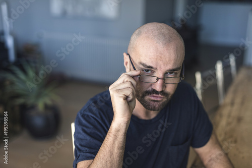 A stylish man with eyeweat is looking at you, with a determined look.