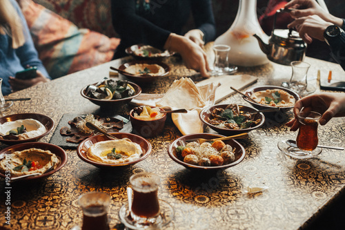 Young happy company of people is eating lebanon food and smokinh shisha. Lebanon cuisine. Traditional meze lunch photo
