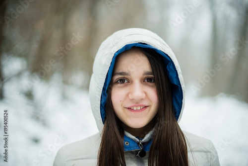 portrait of an 11-year-old girl outside under a snowfall, dressed in a down jacket, a windbreaker photo