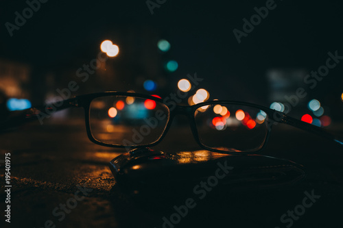 Night cityscape with skyscrapers and city lights as seen through a pair of glasses. Blurred image.