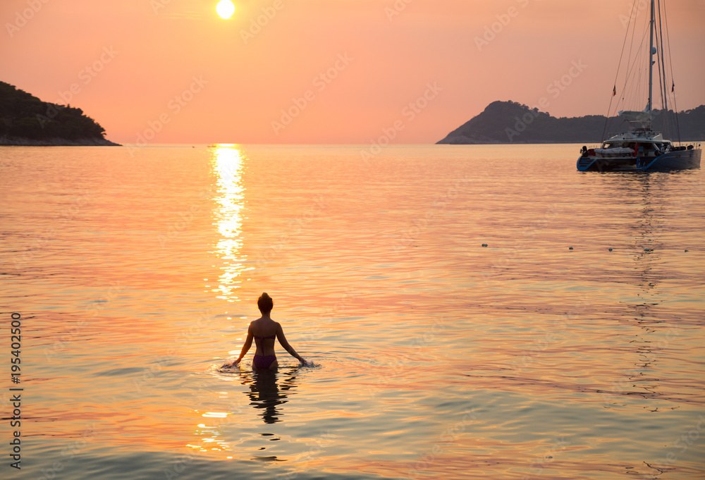 girl swims at sunset