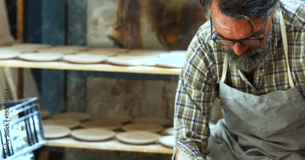 Male potter scrapping out the extra clay from the ceramic bowl Male potter scrapping out the extra clay from the ceramic bowl