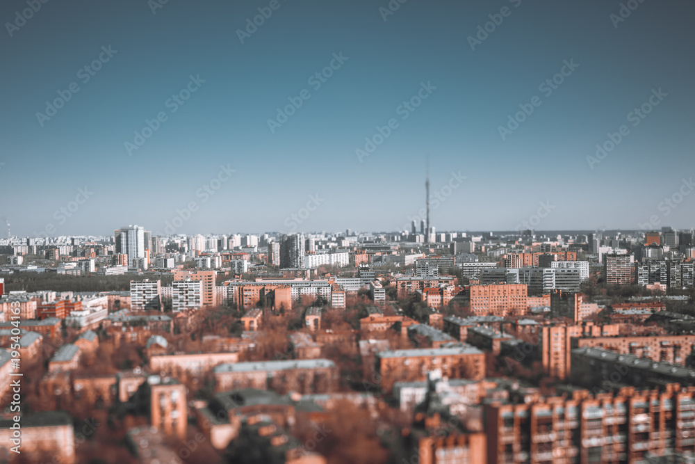 Obraz premium True tilt-shift urban landscape with focus point in the middle of the image: residential districts of Moscow, Russia with many blocks of flats, clear sky and Ostankino tower in defocused background