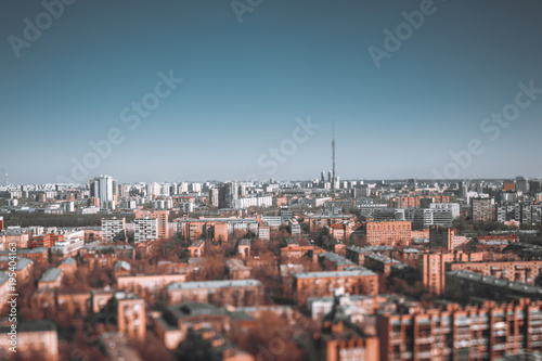 True tilt-shift urban landscape with focus point in the middle of the image: residential districts of Moscow, Russia with many blocks of flats, clear sky and Ostankino tower in defocused background